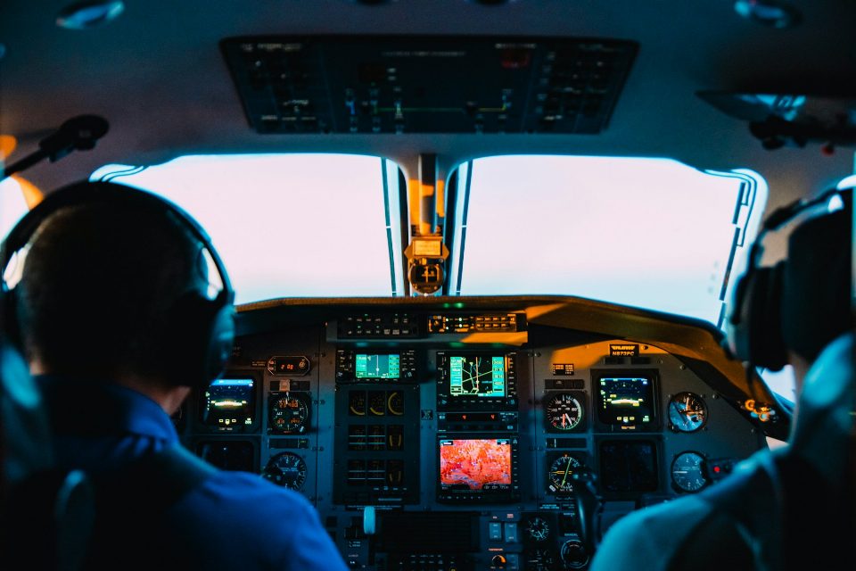A flight instructor and student side by side in a training aircraft cockpit.