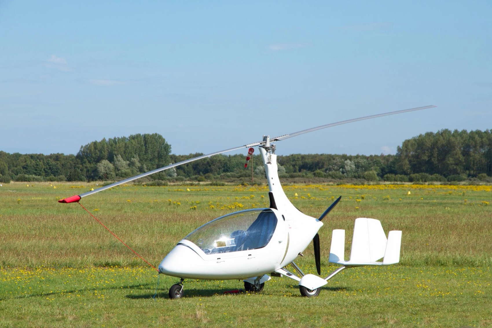 A white gyroplane parked on grass