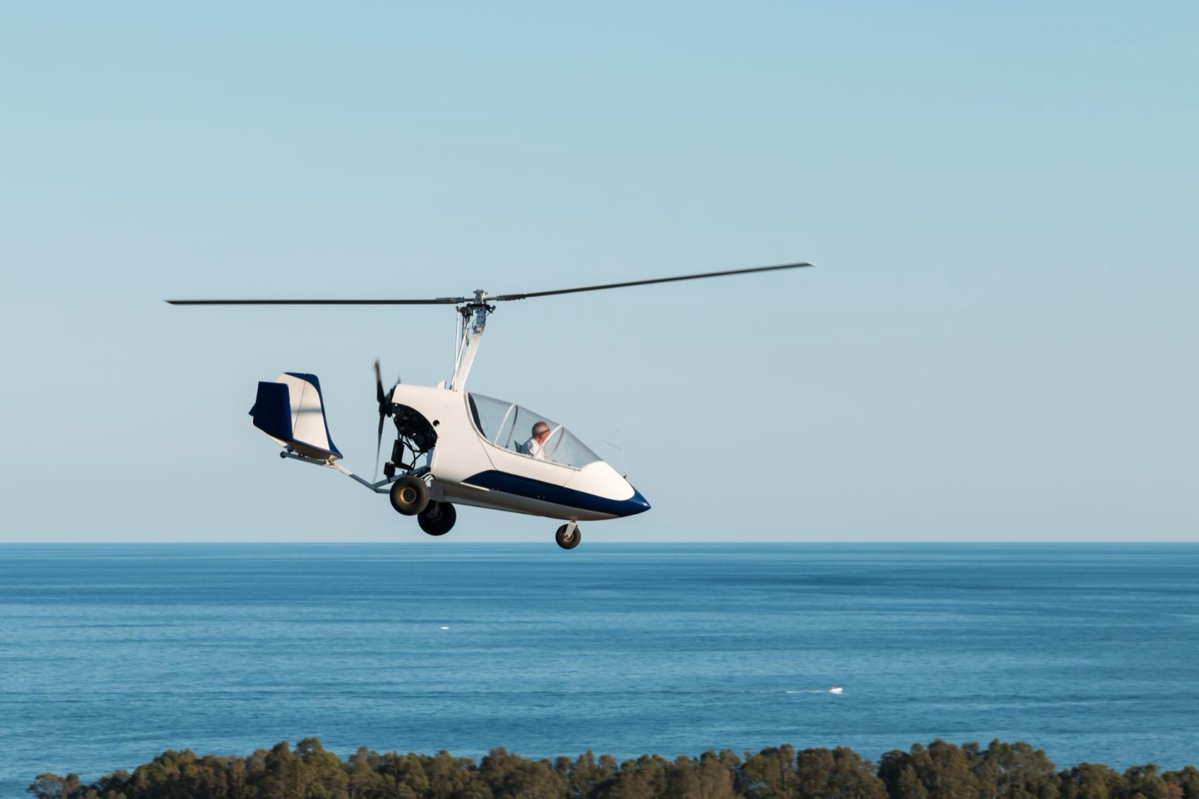 A gyroplane in cruise flight over open water